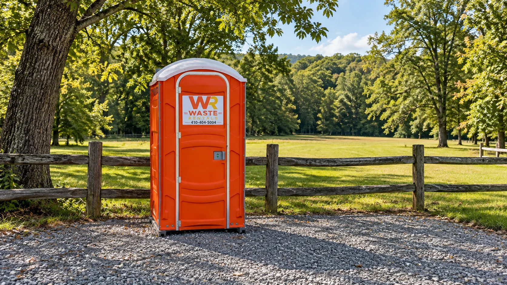 Orange Waste Rentals portable toilet beside a wooded Maryland event field